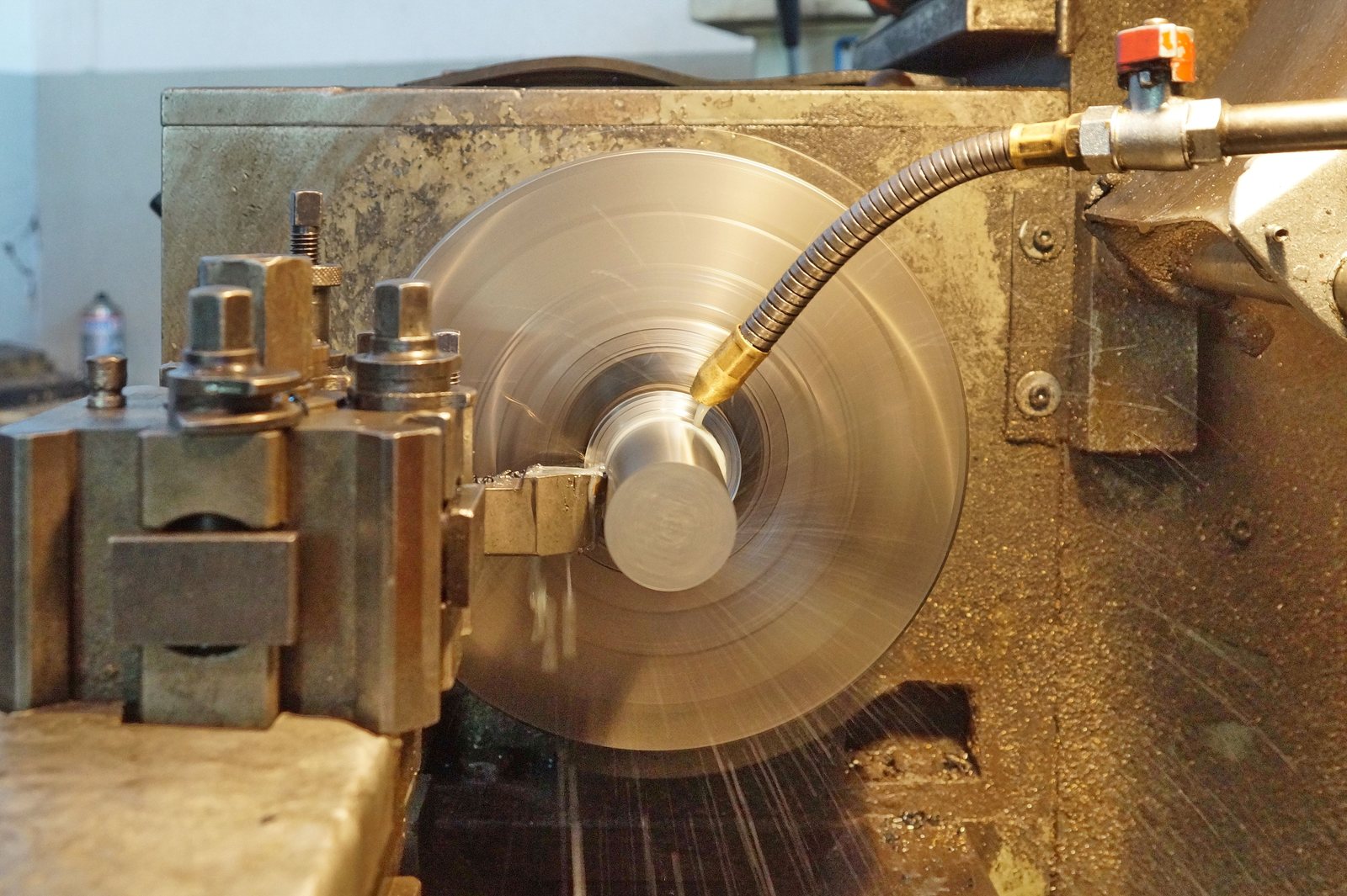 Steel bar being turned on a lathe with coolant flowing