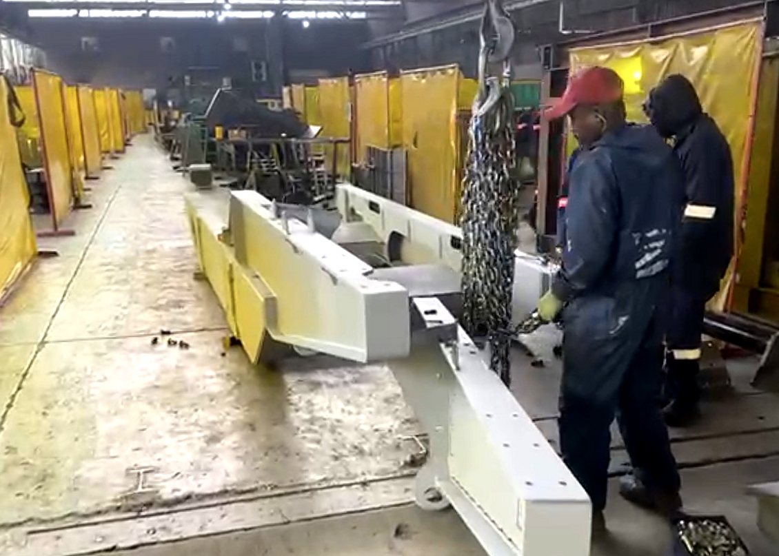 Matcheck team lifting a painted welded machine frame on a chain hoist